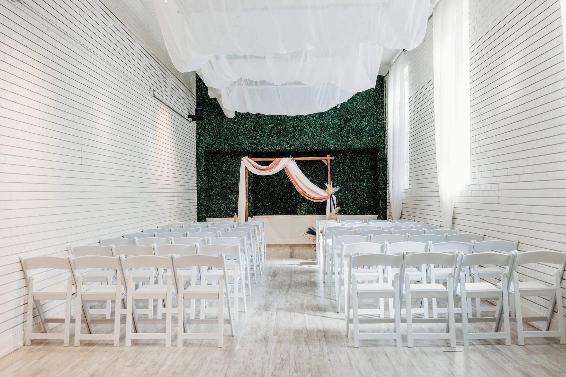 Warm event space with soaring ceilings, soft lighting, and a long banquet table set for a celebration.